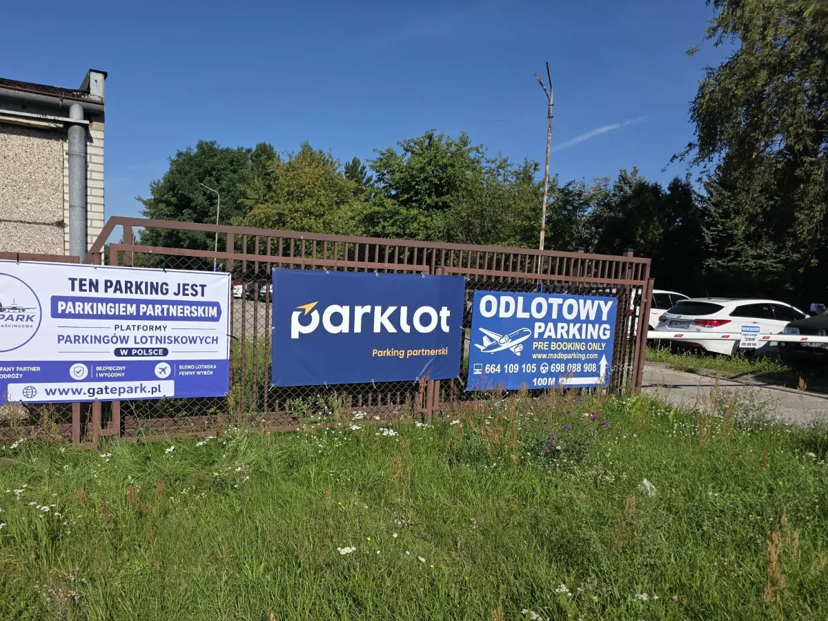 Niebieskie banery Odlotowy Parking z numerami telefonu na ogrodzeniu przy wjeździe na parking przy lotnisku w Łodzi