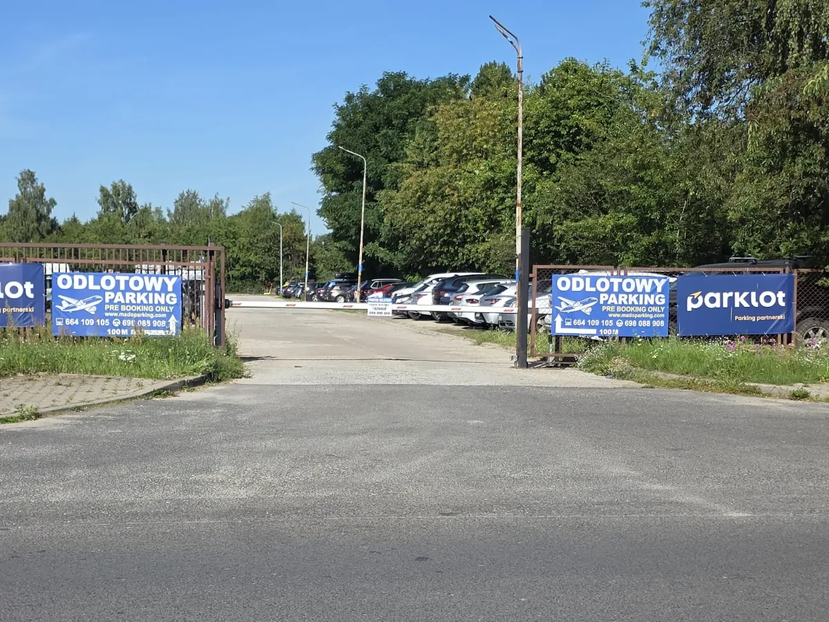 Brama wjazdowa i szlaban Odlotowego Parkingu 800 m od lotniska Łódź-Lublinek, za szlabanem plac z zaparkowanymi samochodami